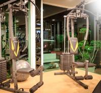 Fitness equipment in apartment construction, green elements, lighting, and mirrored walls.