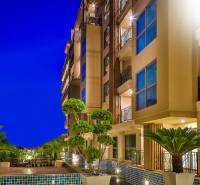 Nighttime construction of apartments in Pattaya with illuminated balconies and green surrounding landscaping.