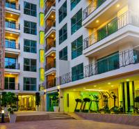 Apartment construction in Pattaya: a modern building with glass balconies and night lighting.