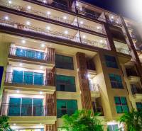 Apartment construction in Pattaya with an illuminated facade and numerous balconies at night.