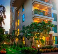 Construction of apartments in Pattaya with a tropical garden and bright balconies in the evening light.