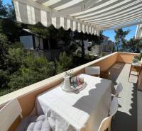 Terrace of a recreational apartment on Šolta, a table with chairs and a view of greenery.