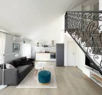 Living room with a sofa, kitchenette, and decorative railing in a holiday apartment.