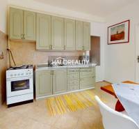 The kitchen of a 4-room apartment with light cabinets, a dining table, and an oven.