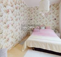 A bedroom in a 4-room apartment with floral wallpaper and a bed.