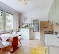 A kitchen in a 4-room apartment with a wooden table, chairs, and a large window with a curtain.