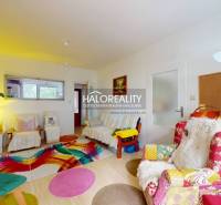 A colorful living room in a 4-room apartment with various patterned chairs and decorations.