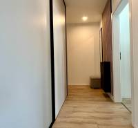 A hallway in a 2-room apartment with light wooden floors and white walls.
