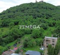 A view of a family house in Brekov surrounded by greenery and a hill with a castle.