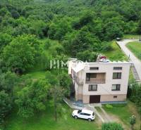 A family house in Brekov surrounded by greenery and forest vegetation, with a car by the house.