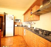 A kitchen in a family house with wooden cabinets, a stove, a microwave, and a refrigerator.