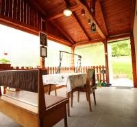 A covered terrace with wooden seating and flowers in a family house.