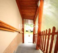 A staircase with a wooden railing leading to the exterior of a family house.