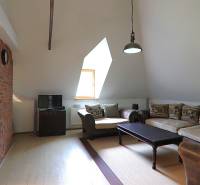 Living room with a sofa, television, and brick wall in a family house.