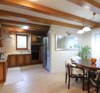 A kitchen in a family house with wooden beams, a dining table, and a plant.