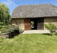 A family house in Podbranč with a stone barn, garden, and manicured lawn.