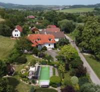 A family house in Podbranč with a swimming pool, surrounded by greenery and countryside.