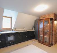 A kitchen in a family house with a black kitchen unit, a refrigerator, and a glass display cabinet.