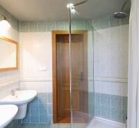 A bathroom in a family house with two sinks, a shower, and wooden doors.