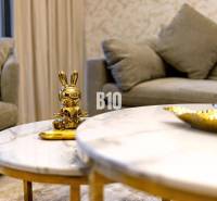 A golden rabbit statue on a marble table in a 3-room apartment with a comfortable gray sofa.