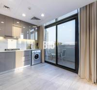 A kitchen in a 3-room apartment with a washing machine and a balcony, light cabinets, large window.