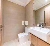 A bathroom in a 3-room apartment with light tiles, a mirror, and a sink.