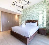 Beautiful bedroom in a 3-room apartment with a bed, botanical wallpaper, and a wooden wardrobe.