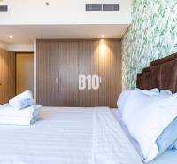 A bedroom with a double bed, a wooden wardrobe, and floral wallpaper in a three-room apartment.