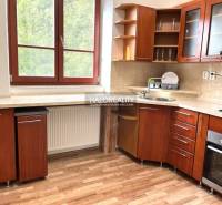 A kitchen in a 3-room apartment with a wooden cabinet, a window overlooking greenery.