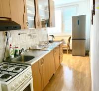 A kitchen with a gas stove and a refrigerator in a 3-room apartment, light-colored countertop.