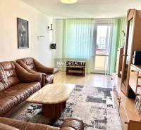 Living room in a three-room apartment with a brown sofa and wooden furniture.