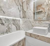 A bathroom in a 4-room apartment with a bathtub and a sink surrounded by marble tiles.