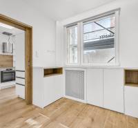 The kitchen of a 4-room apartment with wooden flooring and white cabinets.