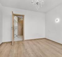 An empty room with a wooden floor and a chandelier in a 4-room apartment.
