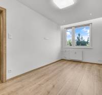An empty room with a wooden floor and a plastic window in a 4-room apartment.