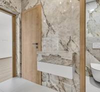 Bathroom with light marble tiles and built-in wall-hung toilet in a 4-room apartment.