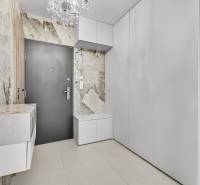 The hallway of a 4-room apartment with white furniture, textured walls, and a chandelier.