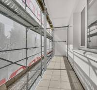 A balcony of a 4-room apartment under renovation with scaffolding and tiles.