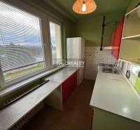A kitchen in a 3-room apartment with green walls, red cabinets, and a large window.