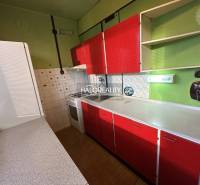 A kitchen in a 3-room apartment with green walls and red cabinets.