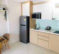 Kitchen corner in a 2-room apartment with a refrigerator, microwave, and wooden furniture.