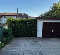 A family house in Lučenec with a garage, a paved courtyard, and greenery around the property.