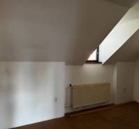 Attic room with a window and a radiator in a family house.