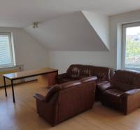 Living room with leather armchairs and a table in a family house, with large windows and blinds.