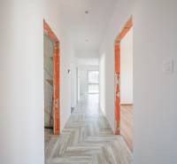 A hallway in a family house with tiles and unfinished door frames.