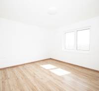 An empty room with a wooden floor and a large window in a family house.