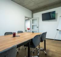 Offices with a wooden table, chairs, a board, and a television.