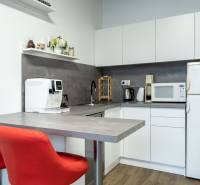 A kitchenette in the office with appliances and red chairs.