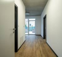 A hallway in offices with a parquet floor and a large window at the end of the room.