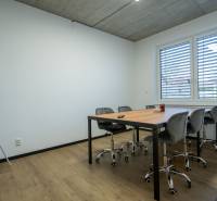 Office with a conference table, chairs, and a flipchart under a window with blinds.
